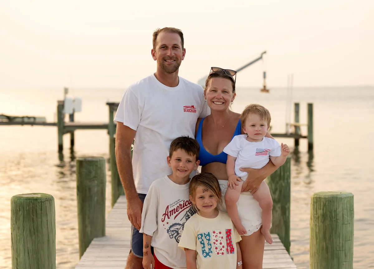 Ross Evans with his wife and their three children on a dock at sunset